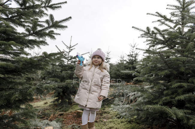 Happy girl playing with water gun on a Christmas tree plantation — Stock Photo