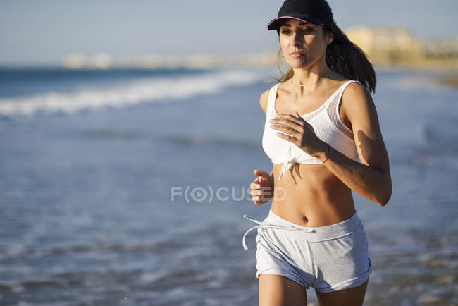 Donna sportiva che corre sulla spiaggia — Foto stock