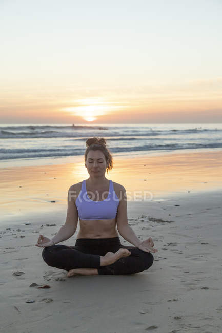 Жінка ввечері медитує на пляжі. — стокове фото