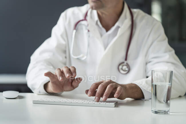Close-up of doctor in medical practice typing on keyboard at desk — Stock Photo
