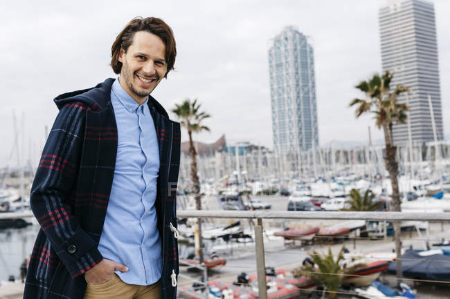 Spain, Barcelona, portrait of smiling man with port and city background — Stock Photo