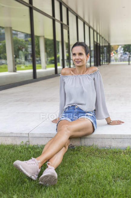 Portrait de femme mûre souriante assise sur la terrasse en été — Photo de stock
