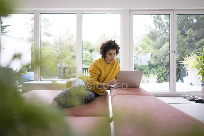 Woman using laptop on couch at home — Stock Photo