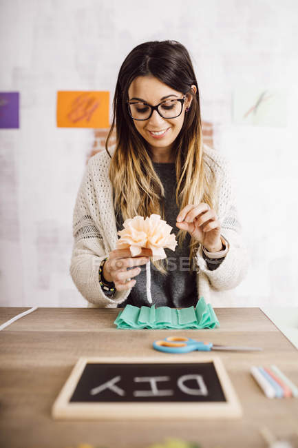 Mujer joven haciendo manualidades en casa, flores de papel - foto de stock