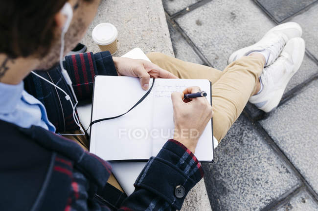 Людина, яка сидить надворі, робить нотатки. — стокове фото