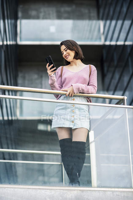 Усміхаючись молодої жінки, дивлячись на мобільний телефон — стокове фото