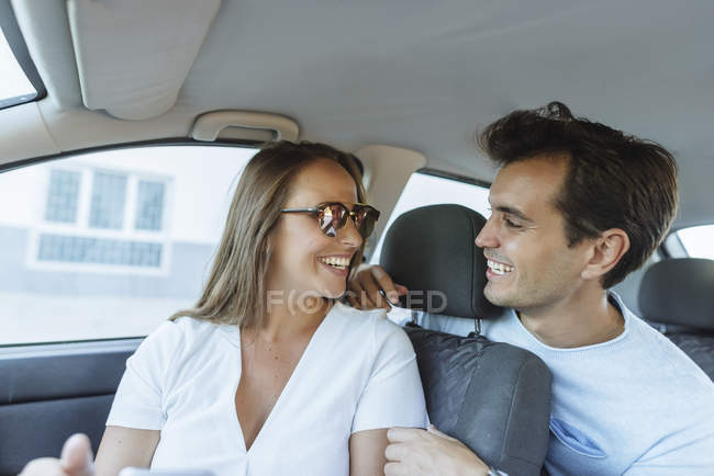 Coppia felice in auto con uomo sul sedile posteriore e donna sul sedile passeggero anteriore — Foto stock