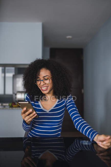 Retrato de la joven feliz en casa mirando el teléfono celular - foto de stock