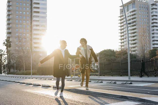 Casal feliz correndo na cidade ao pôr do sol — Fotografia de Stock