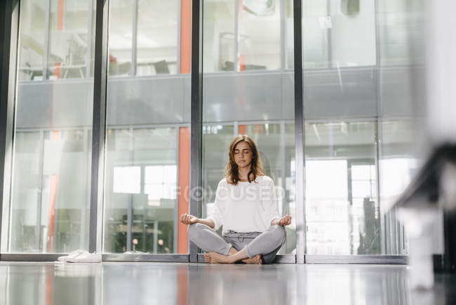 Businesswoman practicing yoga in office, meditating — Stock Photo