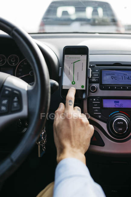 Primo piano dell'uomo con auto tatuata che guida a mano utilizzando il telefono cellulare come sistema di navigazione — Foto stock