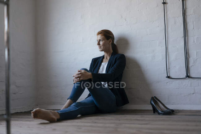 Femme d'affaires pieds nus assis sur le sol dans le bureau — Photo de stock