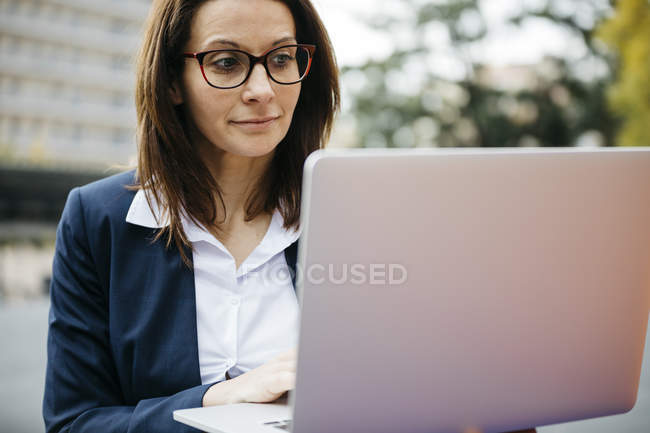 Businesswoman in the city using laptop — Stock Photo