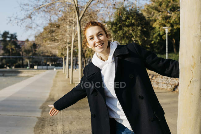 Portrait of happy redheaded young woman in a city park — Stock Photo