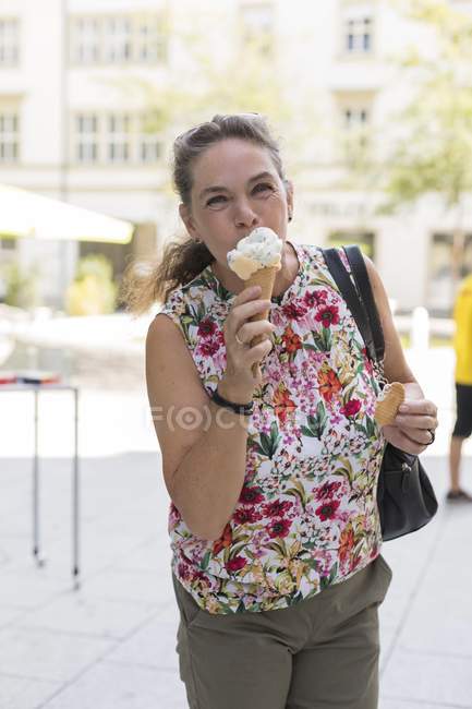 Portrait of mature woman eating ice cream at shopping street — Stock Photo
