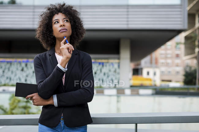 Portrait de femme d'affaires pensant avec ordinateur portable et stylo à l'extérieur — Photo de stock