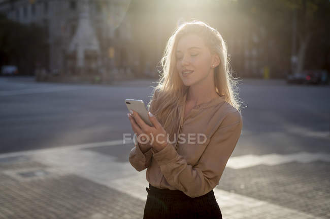 Sourire jeune femme d'affaires utilisant un téléphone portable dans la ville — Photo de stock