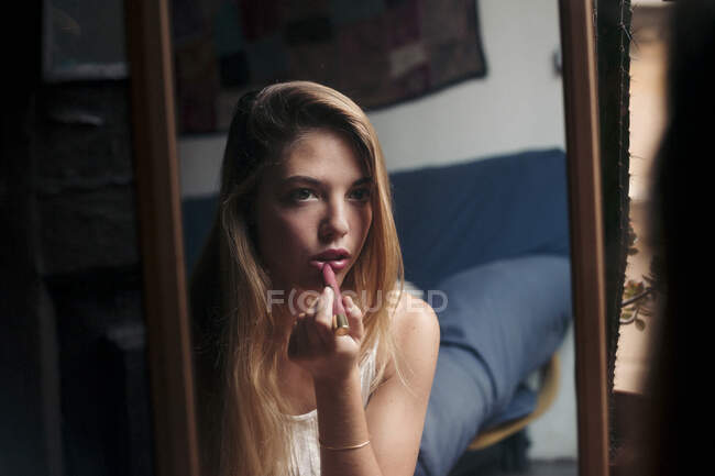 Image miroir de jeune femme appliquant du rouge à lèvres — Photo de stock