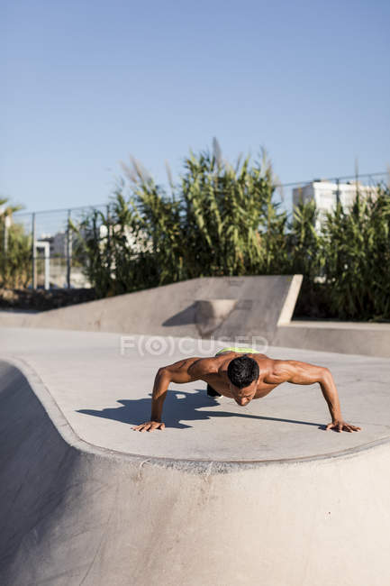 Barechested homem muscular fazendo flexões em um skatepark — Fotografia de Stock