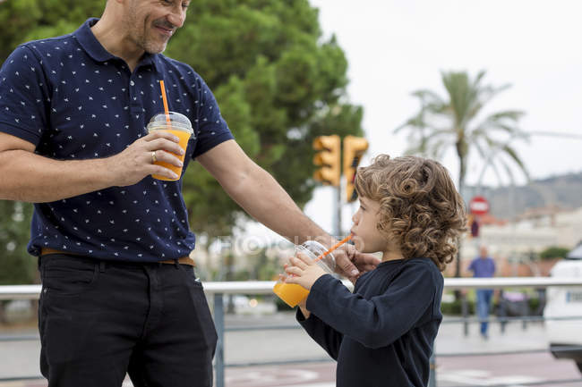 Father and son with soft drinks in the city — Stock Photo