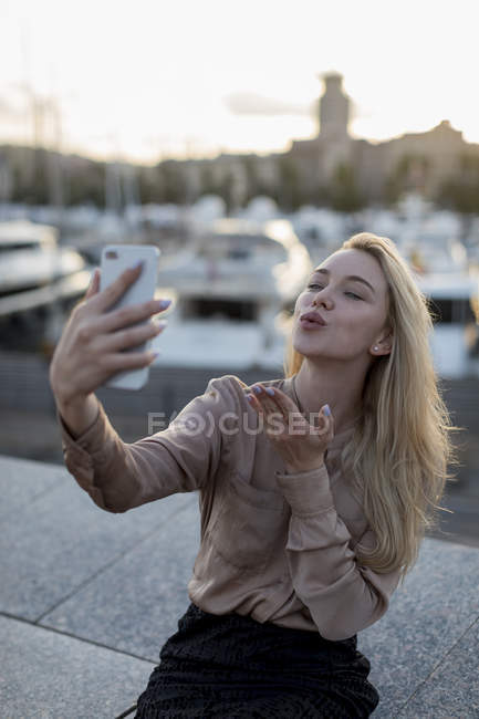 Young Woman Taking A Selfie And Blowing A Kiss At The Waterfront