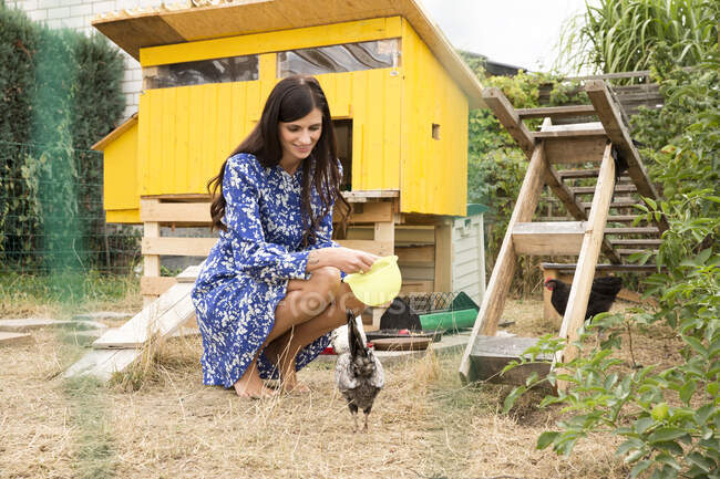 Lächelnde Frau füttert Hühner im Hühnerstall im Garten — Stockfoto