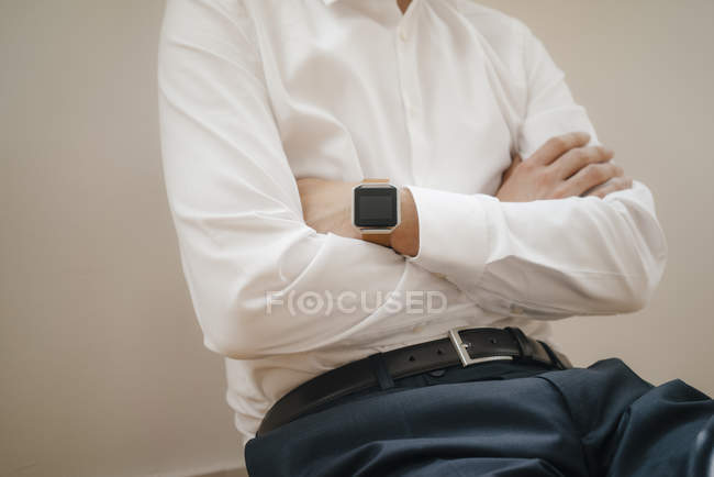 Mid section of a businessman wearing smartwatch with arms crossed — Stock Photo