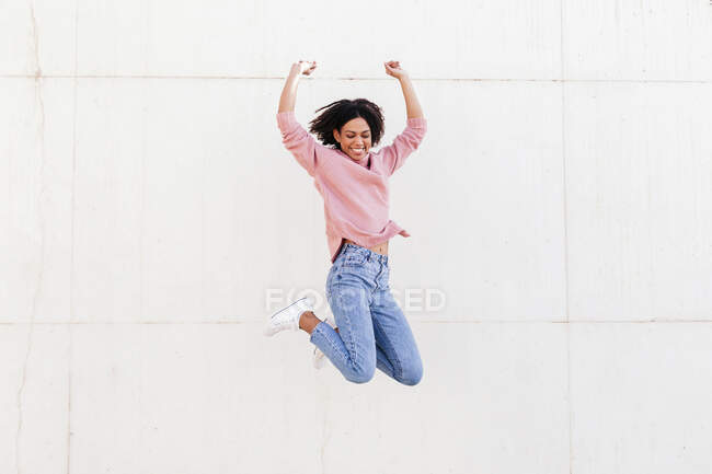 Felice giovane donna saltando in aria su sfondo leggero — Foto stock