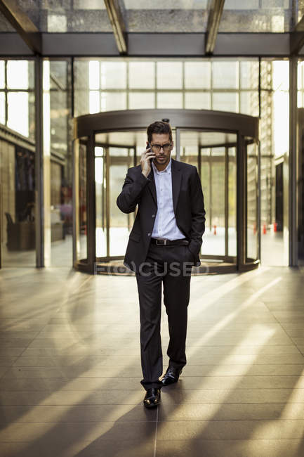 Бизнесмен по мобильному телефону в фойе офисного здания — стоковое фото