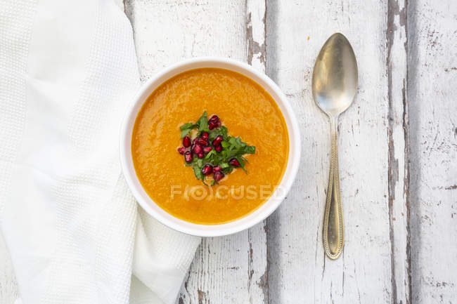 Bowl of carrot ginger coconut soup with topping of parsley and pomegranate seed — Stock Photo