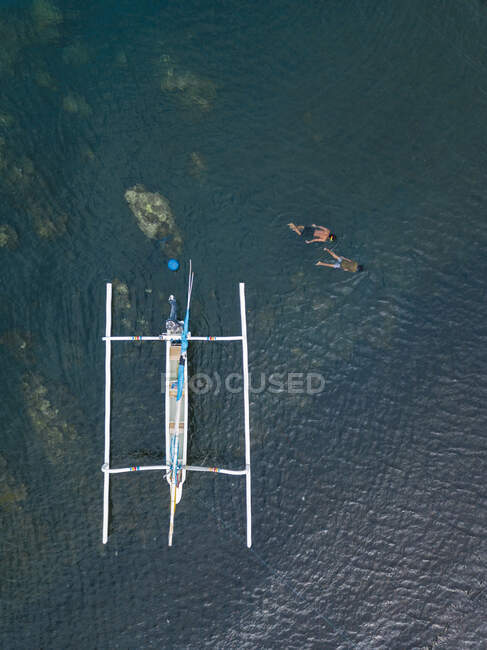 Азійські хлопці плавають в океані, поруч з човном. — стокове фото