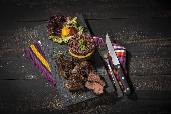 Bifteck de kangourou avec riz rouge et mangue sur plaque d'ardoise — Photo de stock