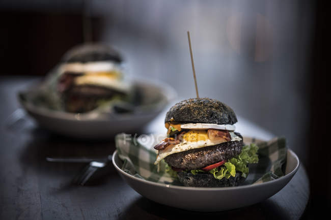 Черные гамбургеры с яйцом и беконом — стоковое фото