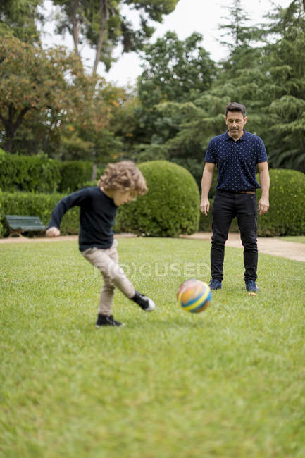 Отец и сын играют в футбол в парке — стоковое фото