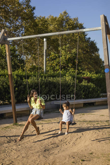 Mãe e filha felizes em um balanço em um playground — Fotografia de Stock