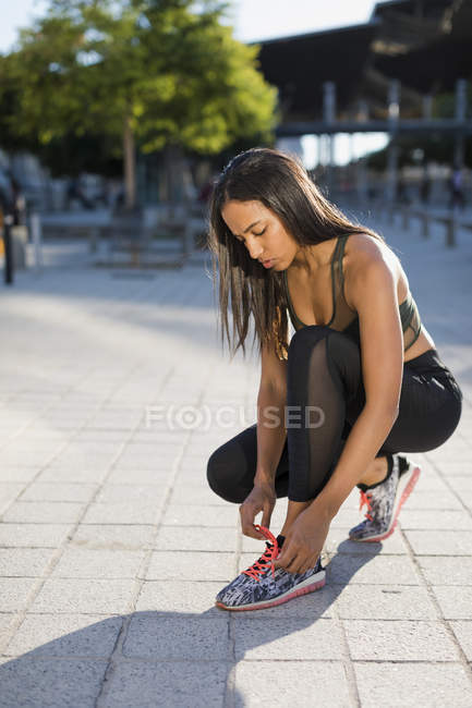 Junge Frau bindet ihre Schuhe vor dem Training — Stockfoto