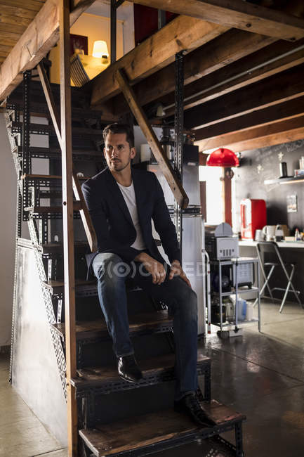 Чоловік сидить на сходах у майстерні. — стокове фото