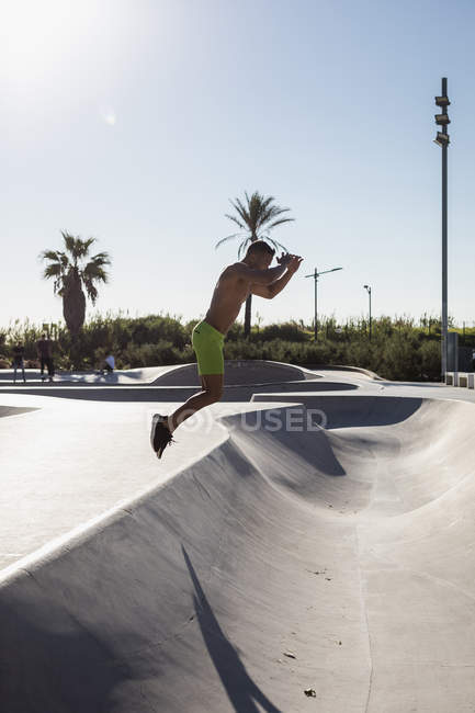 Barechested homem muscular pulando em um parque de skate — Fotografia de Stock