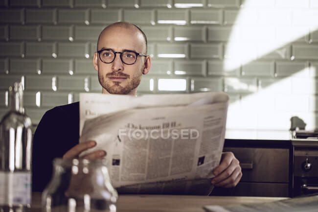 Man sitting in kitchen, reading newspaper — Stock Photo