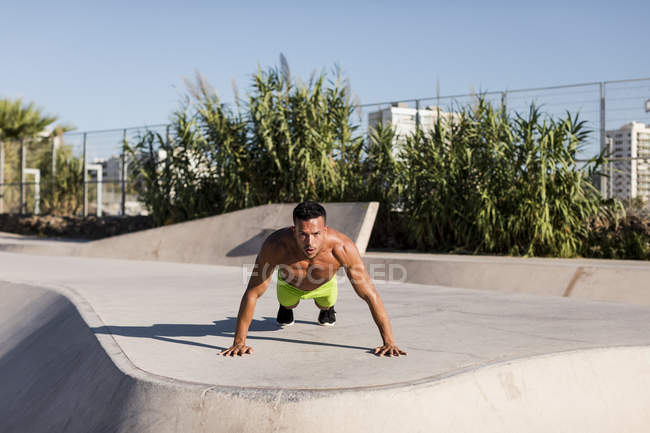 Barechested homem muscular fazendo flexões em um skatepark — Fotografia de Stock