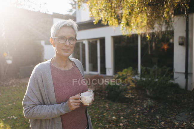 Porträt einer reifen Frau mit einer Tasse Kaffee im Garten — Stockfoto