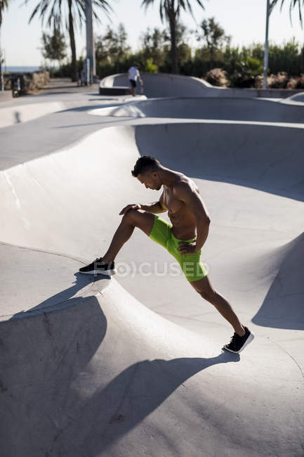 Barechested homem muscular fazendo exercício de alongamento em um parque de skate — Fotografia de Stock