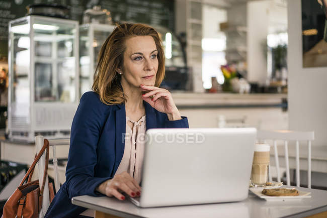 Donna d'affari seduta in caffetteria, a pranzo, al lavoro sul computer portatile — Foto stock