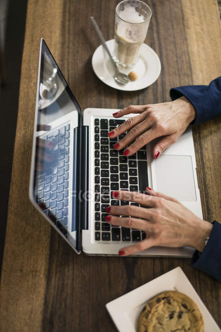 Бізнес-леді сидить у кав'ярні, обідає, працює на ноутбуці — стокове фото