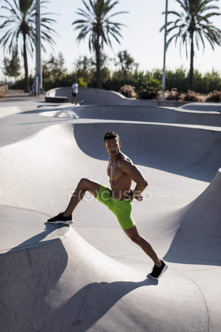 Barechested homem muscular fazendo exercício de alongamento em um parque de skate — Fotografia de Stock