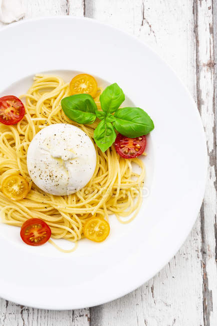 Spaghetti with tomatoes, burrata and basil leaves — Stock Photo
