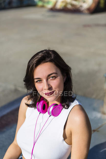 Retrato de jovem sorridente com fones de ouvido na cidade — Fotografia de Stock