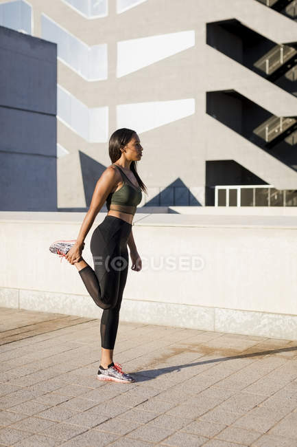 Young woman doing stretching exercise in the city — Stock Photo