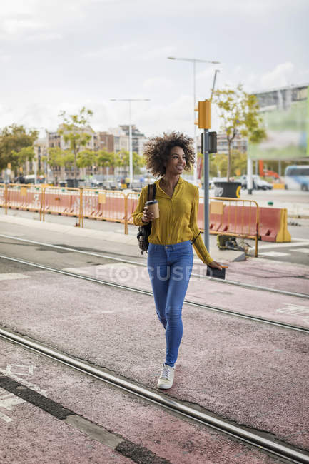 Lächelnde Frau mit Coffee to go und Notizbuch über die Schienen in der Stadt — Stockfoto
