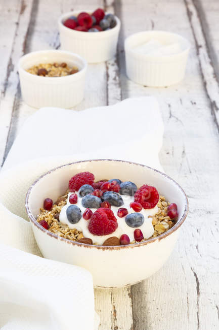 Bowl of muesli with Greek yogurt, popped quinoa, raspberries, blueberries and pomegranate seed — Stock Photo